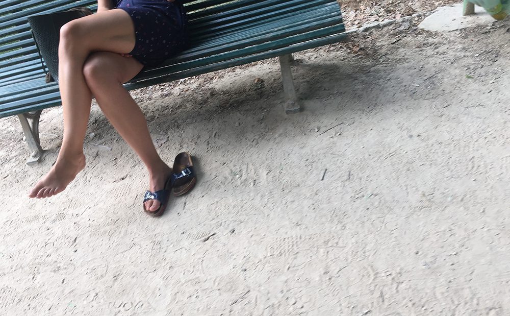 Une femme en claquettes dans un jardin public