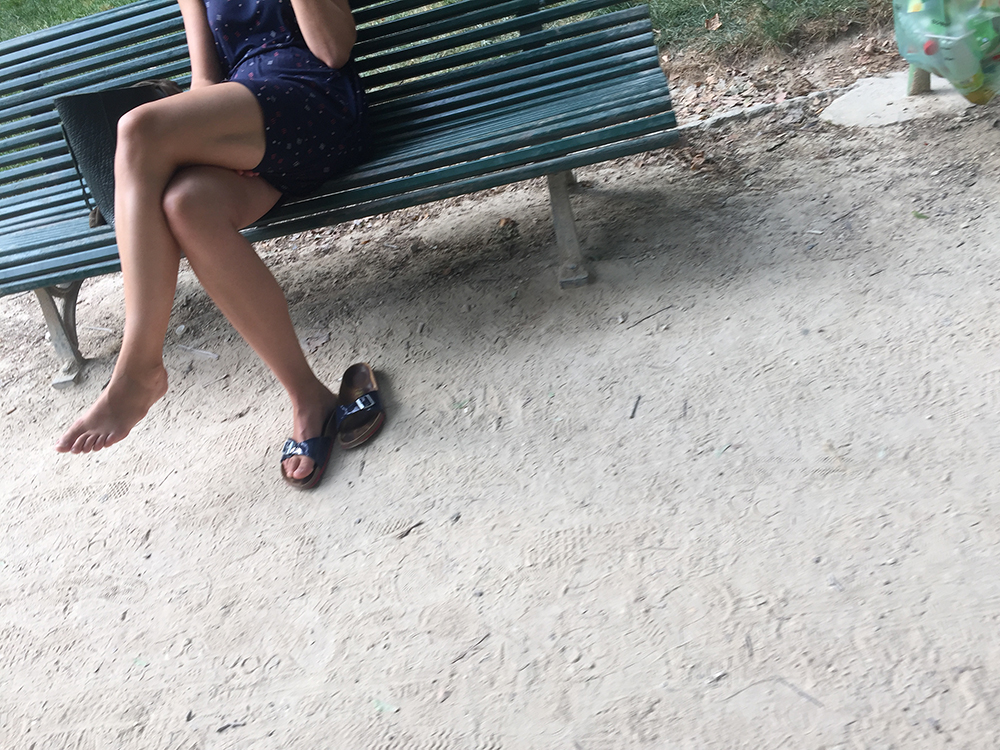 Une femme en claquettes dans un jardin public