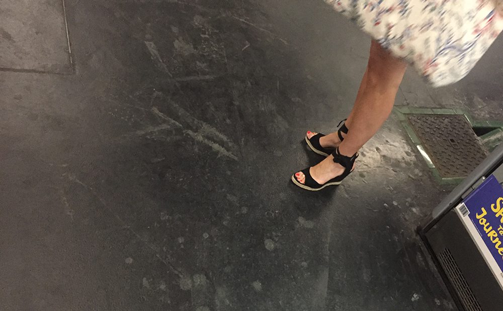 A nice girl in sandals is waiting for the subway