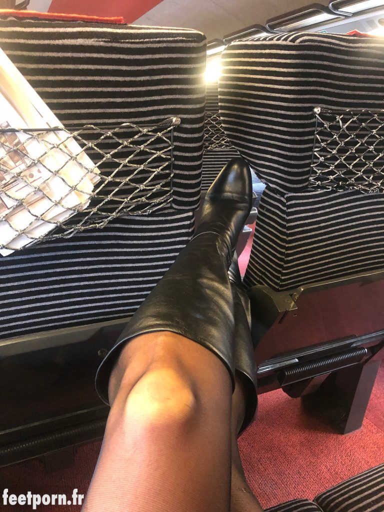 Une femme s'exhibe dans le train avec des bottes en cuir et des collanst noirs