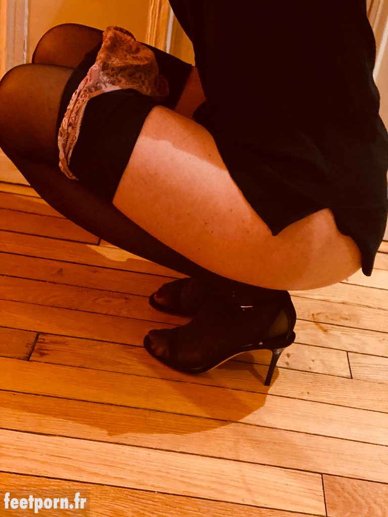 Elle porte des collants noirs et des sandales de luxe
