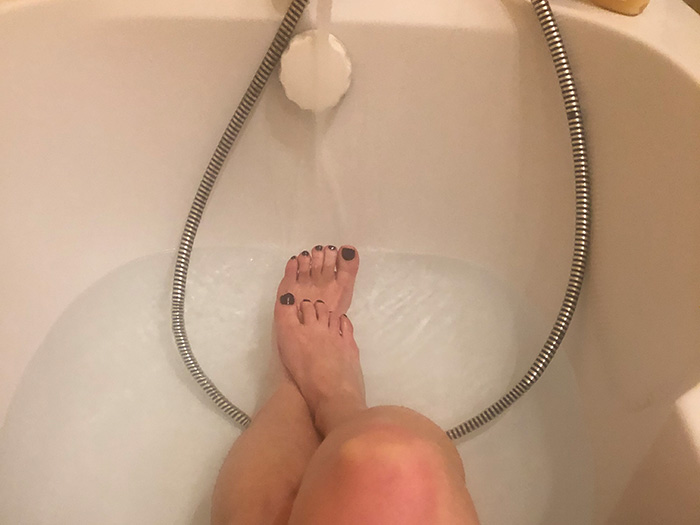 Nue dans sa baignoire elle montre ses pieds